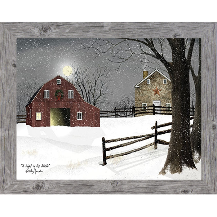 Gray framed landscape Billy Jacobs wall art print of a red barn with a Christmas wreath and glowing door on a moonlit snowy night with a stone farmhouse and split rail fence titled "A Light in the Stable"